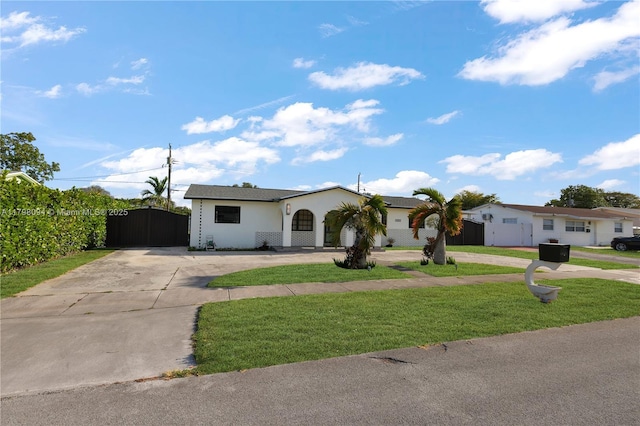 single story home featuring a front yard, stucco siding, curved driveway, and a gate