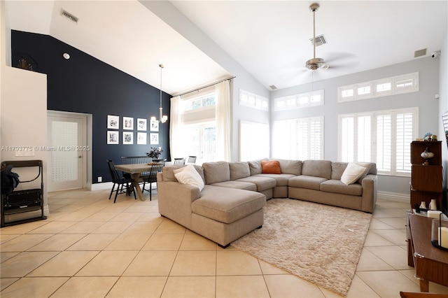 living area featuring light tile patterned flooring, a wealth of natural light, high vaulted ceiling, and a ceiling fan