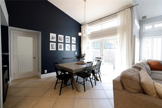 dining space with a healthy amount of sunlight, high vaulted ceiling, and light tile patterned floors