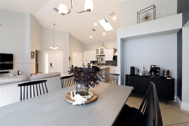 dining space with light tile patterned flooring, high vaulted ceiling, visible vents, an inviting chandelier, and baseboards