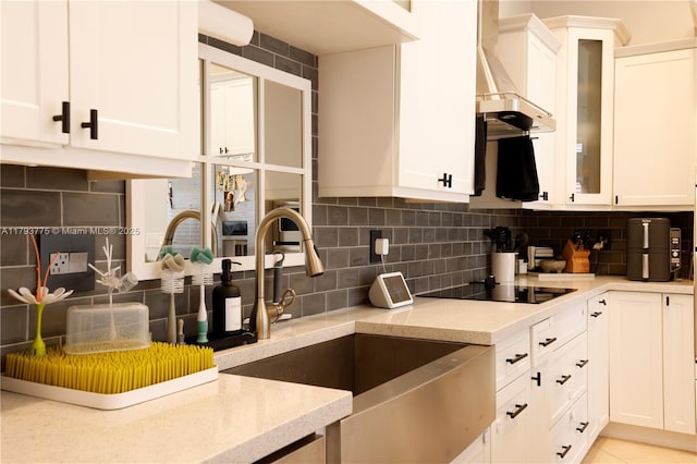 kitchen featuring a sink, white cabinetry, tasteful backsplash, and black electric stovetop
