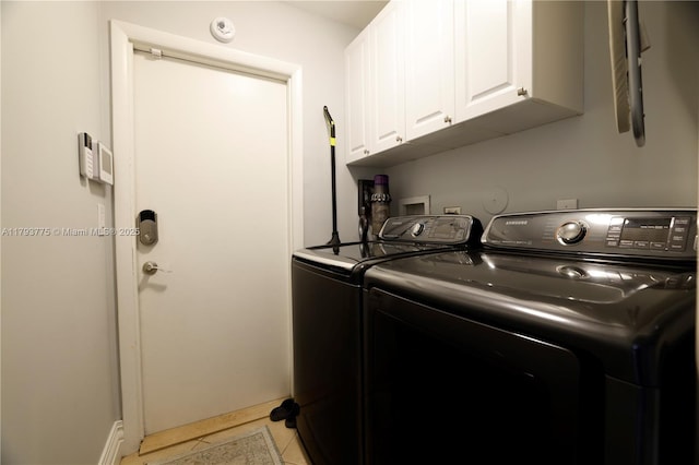 laundry area with washing machine and clothes dryer, light tile patterned floors, and cabinet space