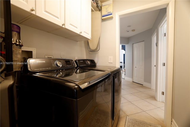 washroom featuring cabinet space, washing machine and clothes dryer, baseboards, and light tile patterned flooring