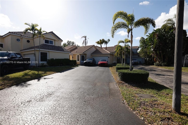 view of front of home with a tile roof, a garage, stucco siding, and driveway