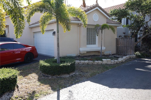 view of front of house featuring an attached garage, stucco siding, and a tiled roof
