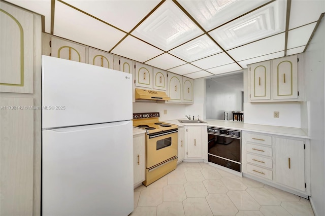 kitchen featuring freestanding refrigerator, under cabinet range hood, black dishwasher, a sink, and range with electric stovetop