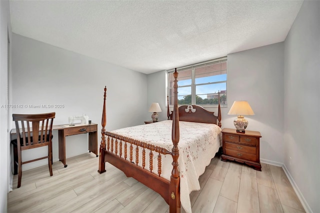 bedroom featuring light wood-type flooring, baseboards, and a textured ceiling