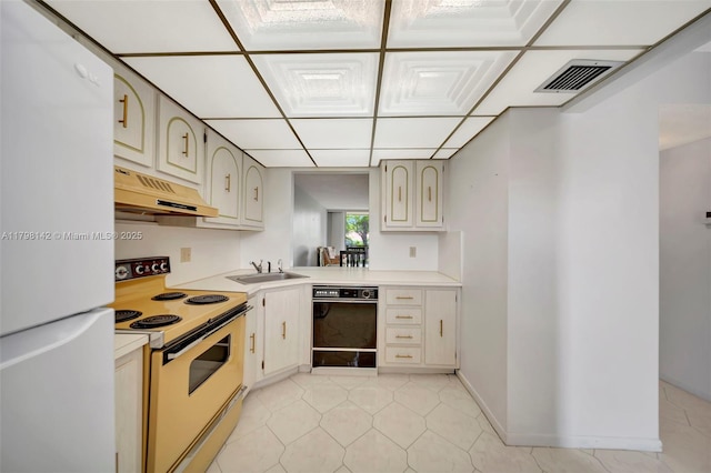 kitchen with under cabinet range hood, white appliances, visible vents, a sink, and light countertops