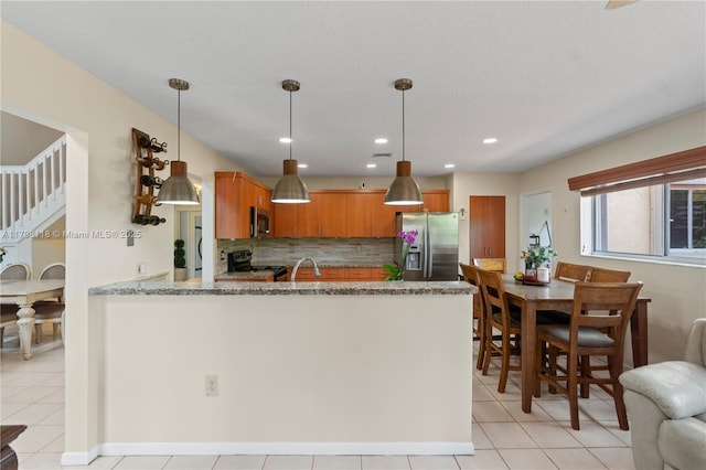 631 NW 205th Ave, Pembroke Pines, FL 33029 - kitchen with a sink, a peninsula, stainless steel appliances, brown cabinets, and backsplash