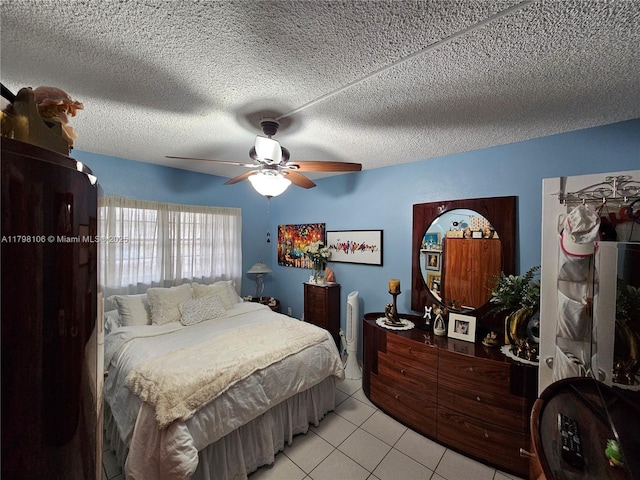 bedroom featuring light tile patterned floors, a ceiling fan, and a textured ceiling