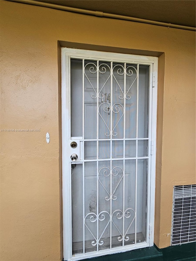 view of exterior entry with stucco siding and visible vents