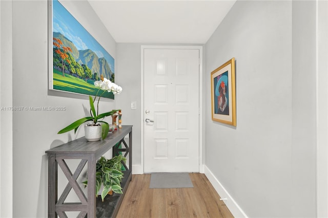 doorway featuring baseboards and wood finished floors