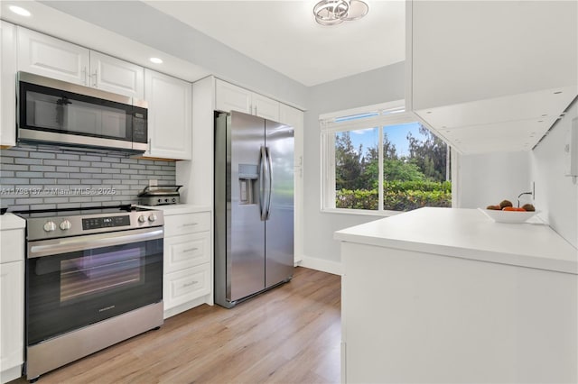 kitchen with white cabinets, light wood-style flooring, appliances with stainless steel finishes, and tasteful backsplash