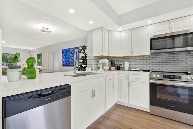 kitchen featuring white cabinets, light countertops, appliances with stainless steel finishes, and a sink