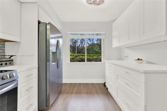 kitchen featuring light wood finished floors, white cabinets, baseboards, light countertops, and appliances with stainless steel finishes