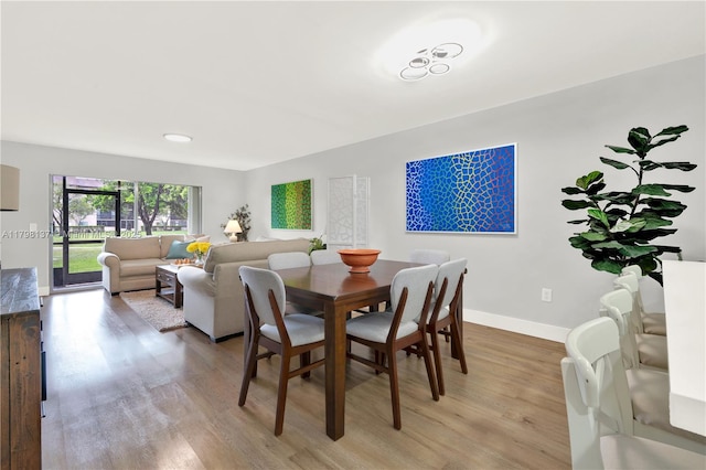 dining space featuring light wood-style flooring and baseboards