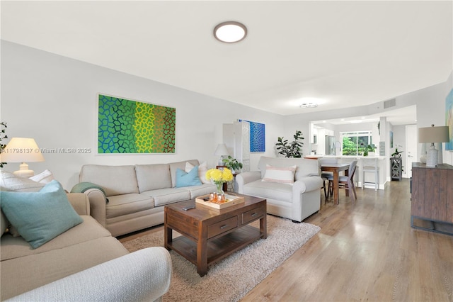 living area with light wood-style floors and visible vents