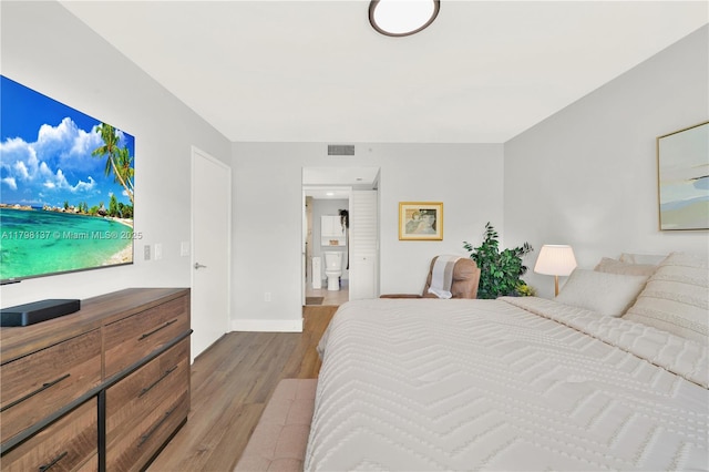 bedroom featuring wood finished floors, baseboards, and ensuite bathroom