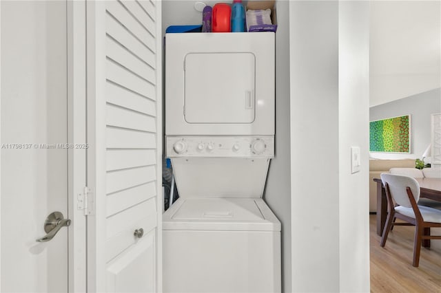 washroom featuring stacked washer and clothes dryer and light wood-type flooring