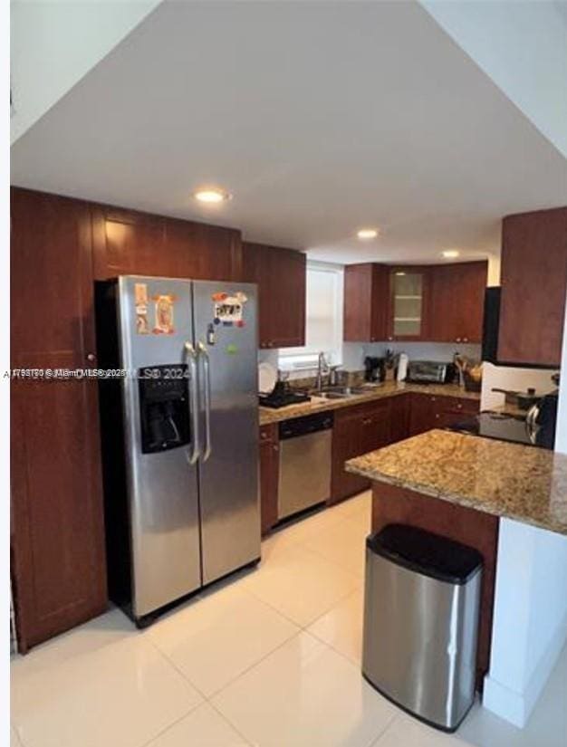 kitchen featuring glass insert cabinets, a sink, stainless steel appliances, light stone counters, and recessed lighting