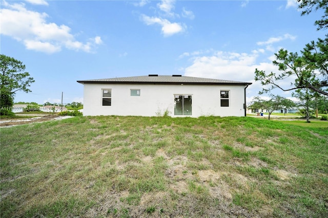 back of property with a yard and stucco siding