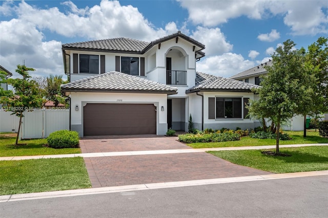 mediterranean / spanish home featuring fence, a garage, a tiled roof, a front lawn, and decorative driveway