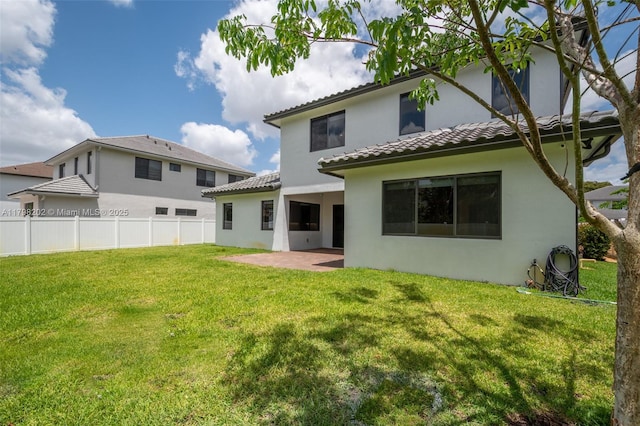 back of house with a patio, a tiled roof, stucco siding, fence, and a yard