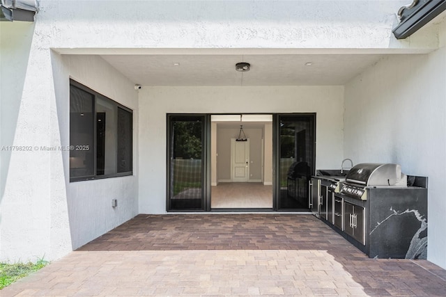 entrance to property with a patio area, an outdoor kitchen, and stucco siding