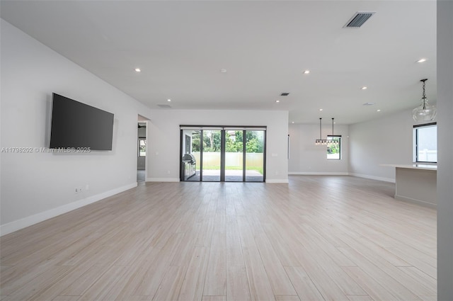 unfurnished living room with a healthy amount of sunlight, light wood-type flooring, visible vents, and recessed lighting