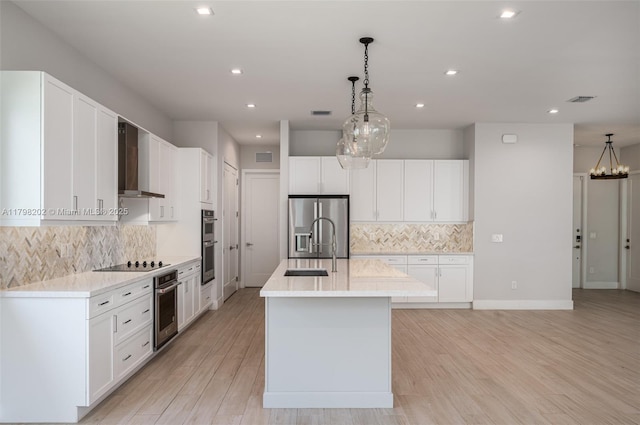kitchen with wall chimney range hood, appliances with stainless steel finishes, visible vents, and tasteful backsplash
