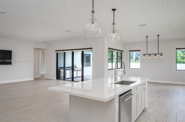kitchen featuring a sink, a kitchen island with sink, light wood-type flooring, open floor plan, and white cabinets