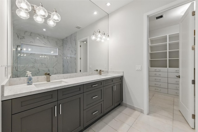 full bathroom featuring a sink, a walk in closet, a marble finish shower, visible vents, and double vanity
