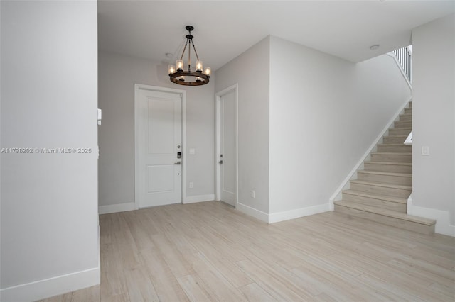 foyer with baseboards, stairs, an inviting chandelier, and wood finished floors