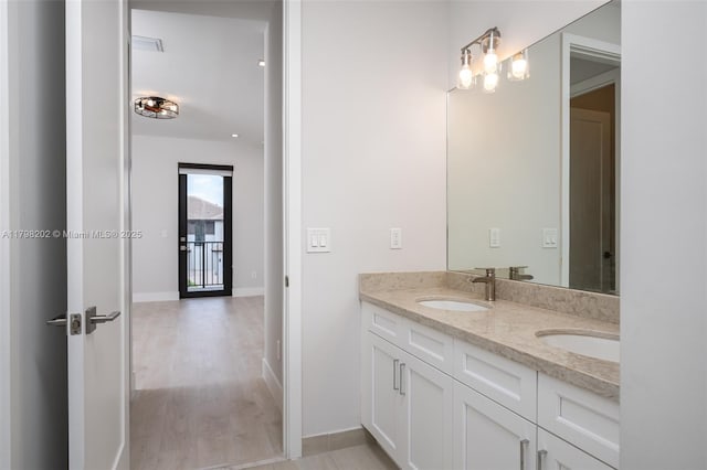bathroom featuring double vanity, wood finished floors, baseboards, and a sink