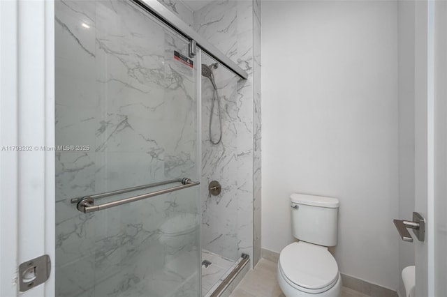 bathroom featuring toilet, a marble finish shower, and baseboards