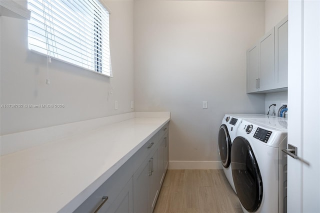 laundry area featuring baseboards, cabinet space, light wood-type flooring, and independent washer and dryer