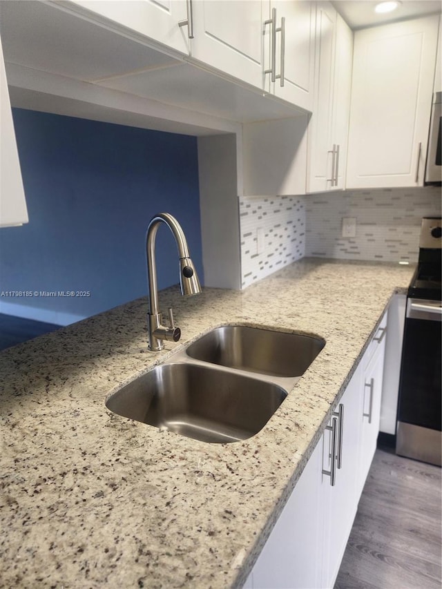 1401 SW 128th Ter Unit 305H, Pembroke Pines, FL 33027 - kitchen with stainless steel electric range oven, white cabinetry, light stone countertops, backsplash, and dark wood-type flooring