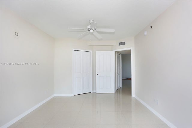 spare room with light tile patterned floors, visible vents, baseboards, and a ceiling fan
