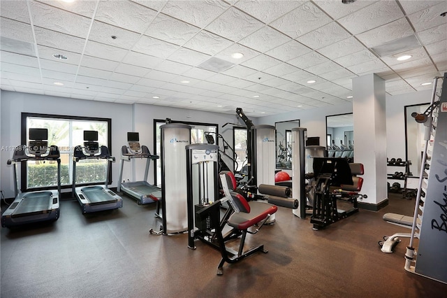 workout area featuring baseboards and a paneled ceiling