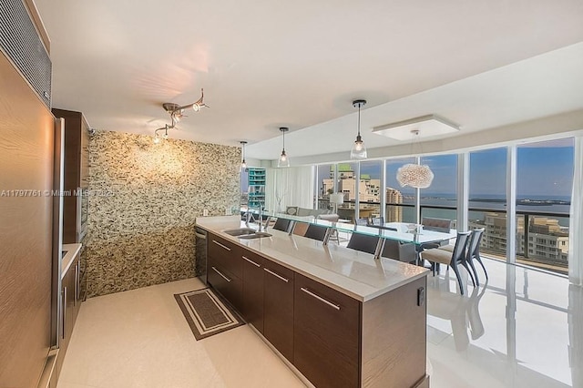 kitchen featuring a sink, a water view, dark brown cabinets, modern cabinets, and pendant lighting