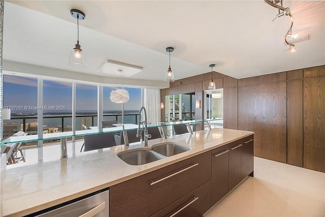 kitchen featuring dishwasher, a sink, decorative light fixtures, and light countertops
