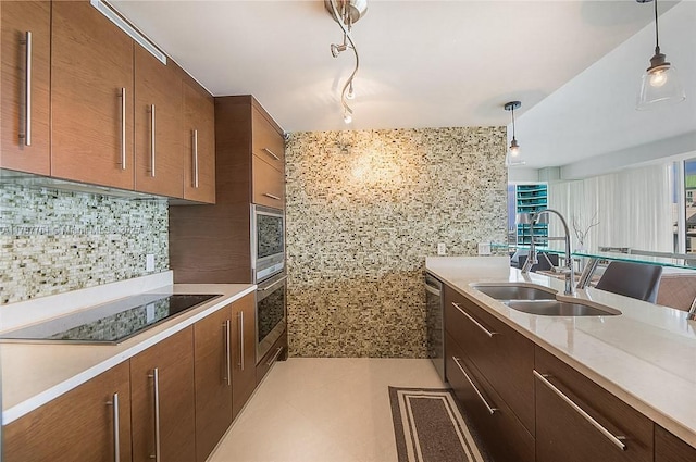 kitchen with a sink, stainless steel appliances, pendant lighting, tasteful backsplash, and modern cabinets