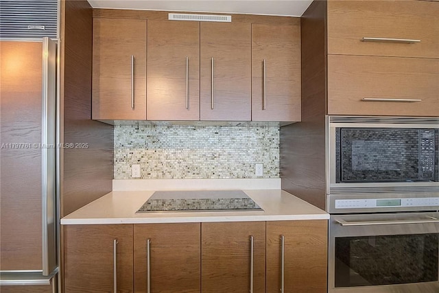 kitchen with oven, modern cabinets, light countertops, and built in microwave