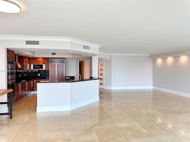 kitchen with crown molding, dark countertops, stainless steel appliances, and visible vents