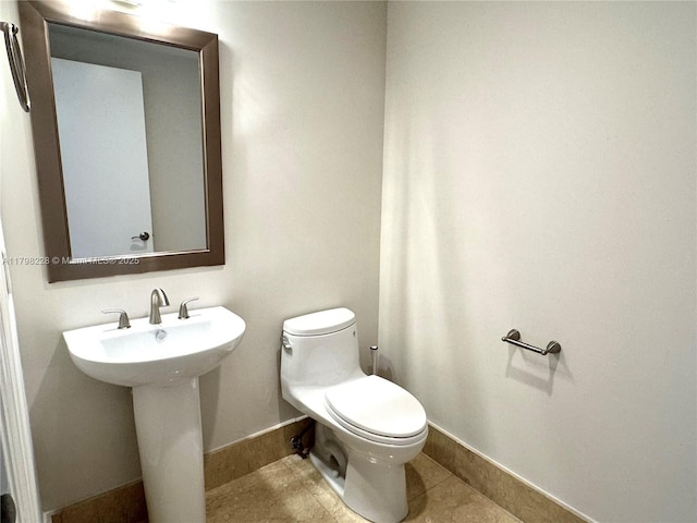 bathroom with a sink, tile patterned flooring, toilet, and baseboards