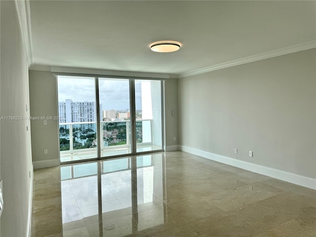 empty room featuring crown molding, a city view, and baseboards