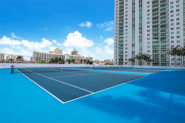view of tennis court featuring a view of city and fence