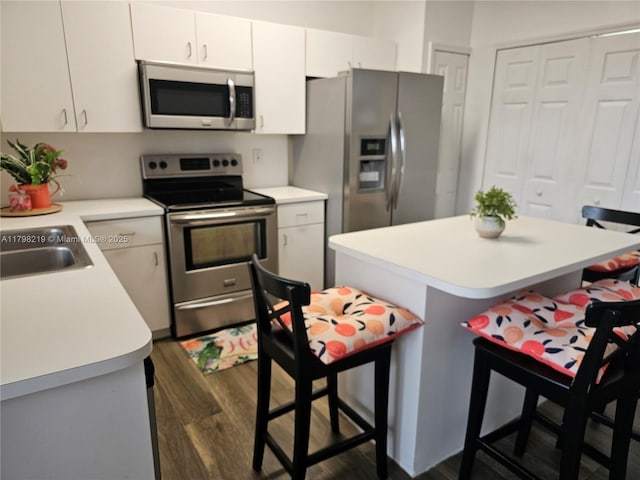 6101 NW 114th Ct Unit 124, Doral, FL 33178 - kitchen with appliances with stainless steel finishes, light countertops, a breakfast bar, and dark wood finished floors