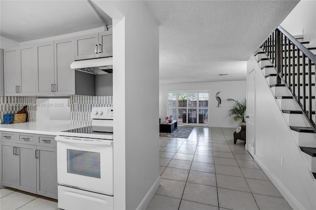 8425 SW 137th Ave Unit 8425, Miami, FL 33183 - kitchen with white range with electric stovetop, under cabinet range hood, backsplash, light tile patterned floors, and light countertops