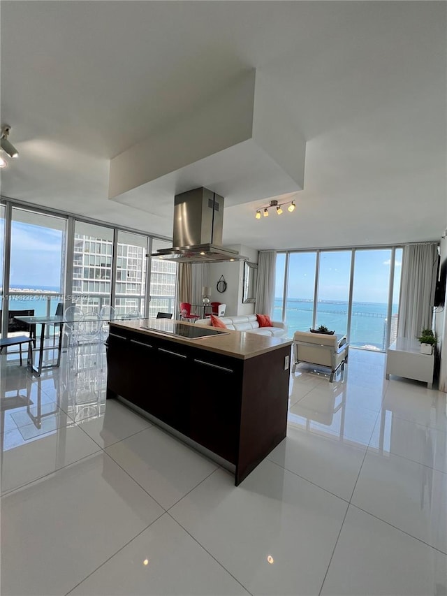 kitchen featuring island range hood, expansive windows, open floor plan, light tile patterned floors, and black electric cooktop